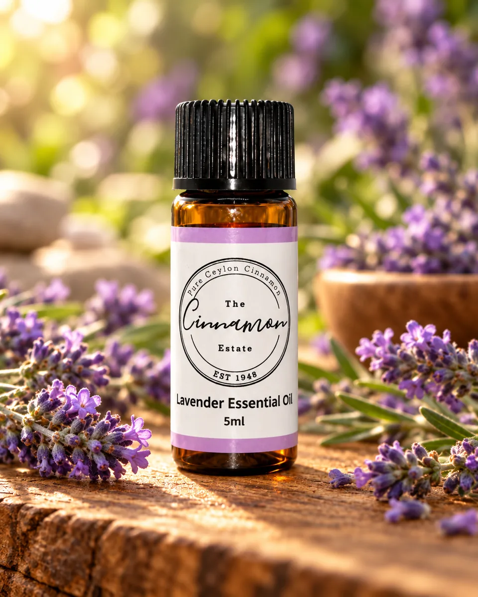 An amber dropper bottle of The Cinnamon Estate pure lavender essential oil, with a lilac striped label, on a weathered wooden board among lavender sprigs.