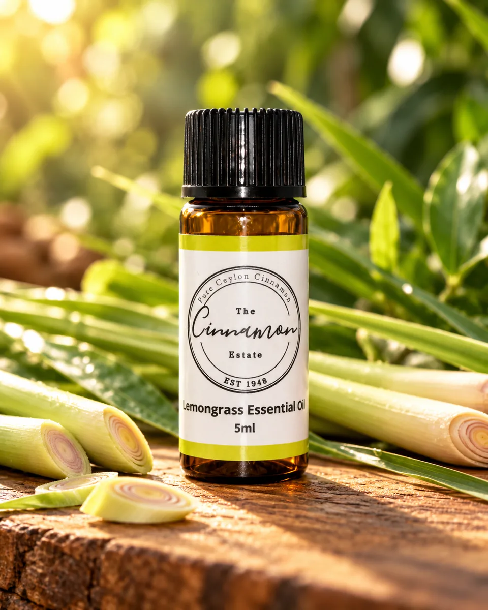 An amber dropper bottle of The Cinnamon Estate lemongrass essential oil, with a chartreuse striped label, on a weathered wooden board beside cut lemongrass stalks.